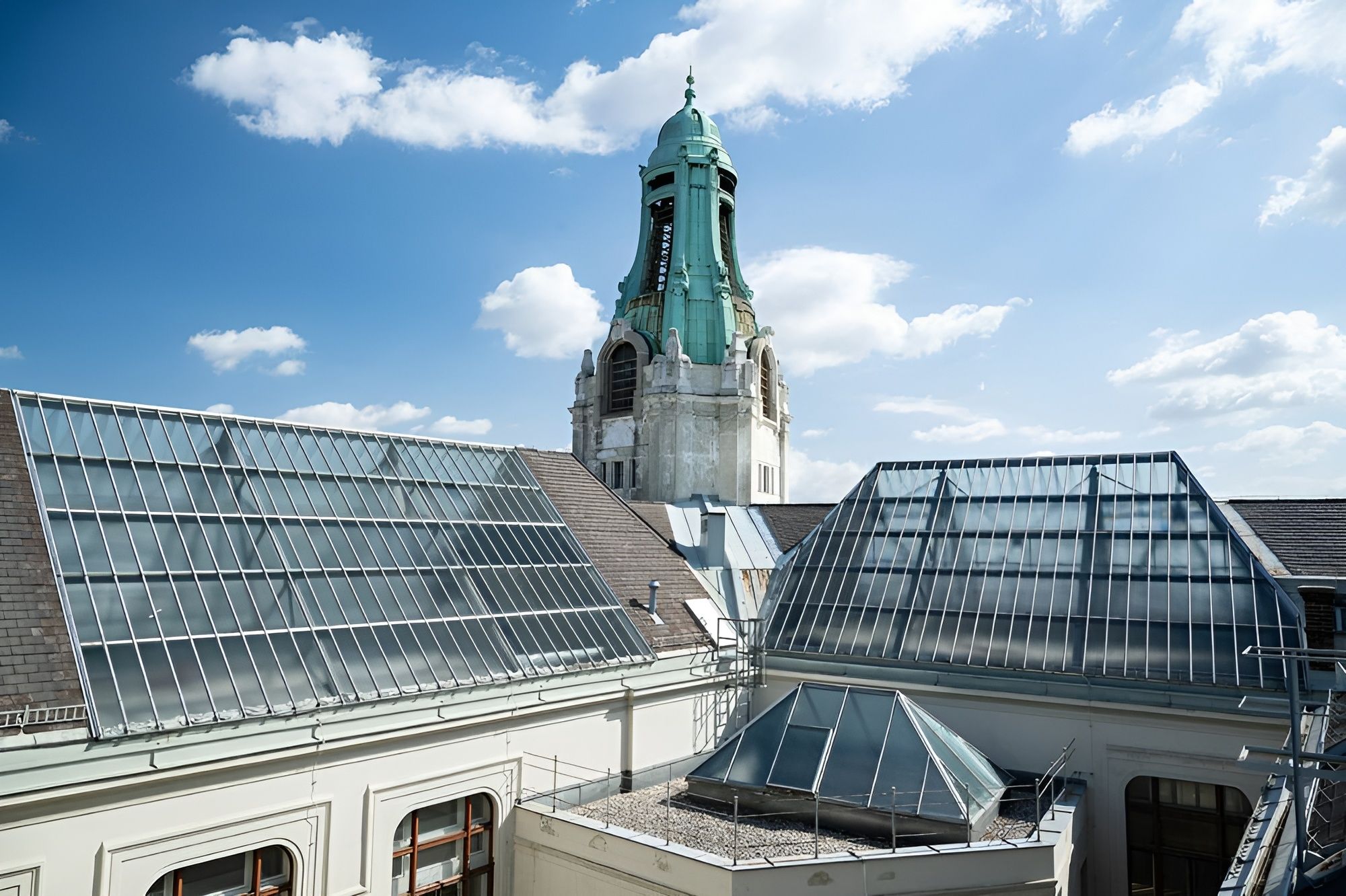 Eine Dachansicht mit Sonnenkollektoren und einem historischen Turm vor blauem Himmel.